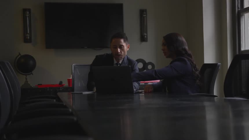 Man and woman sit at a large table in a conference room