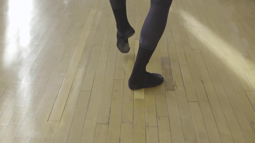 A dancer is practicing on the wood floor