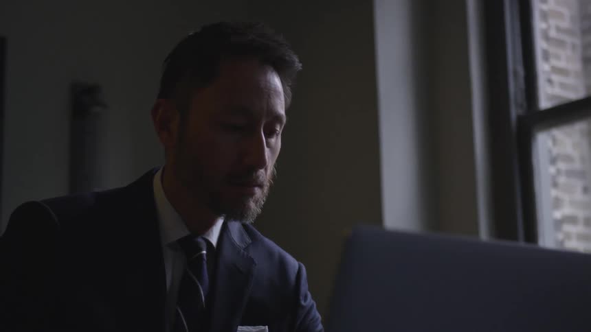 A man in a suit works on a laptop