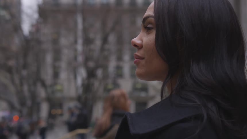 The woman smiles as people walk by her in the city