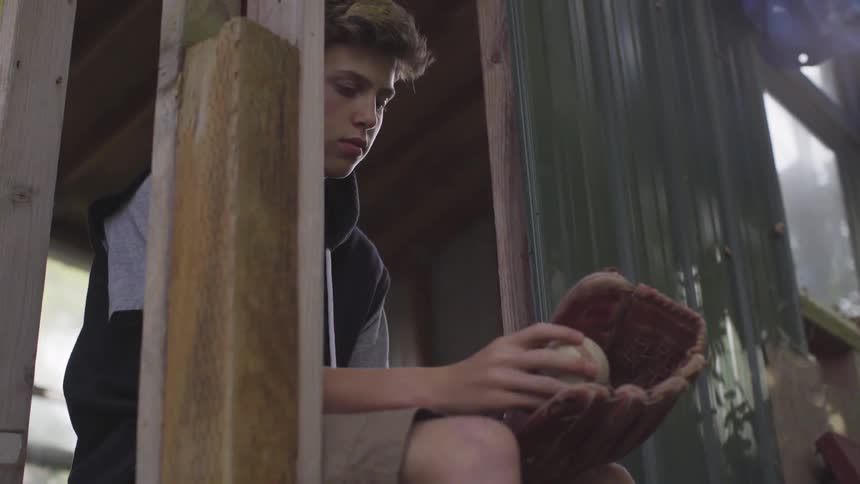 A teenage boy tosses a baseball into his mitt