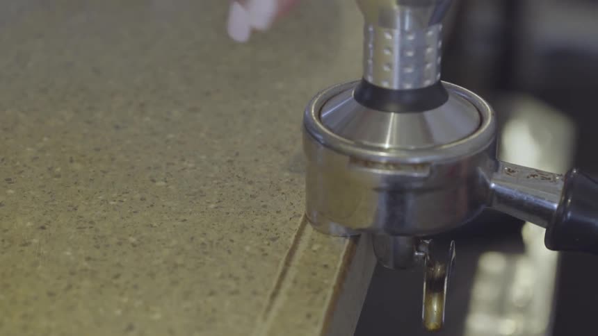 Woman spins a device and removes it from a container of coffee grounds