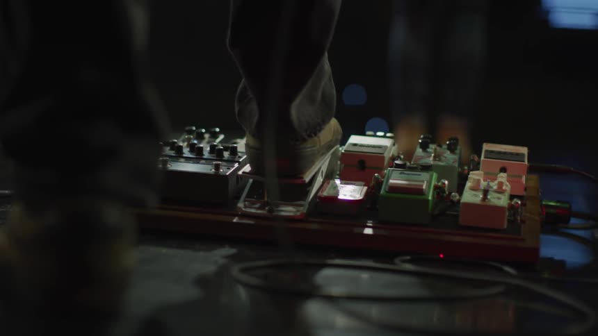 A musician on a stage has his foot on a control pedal