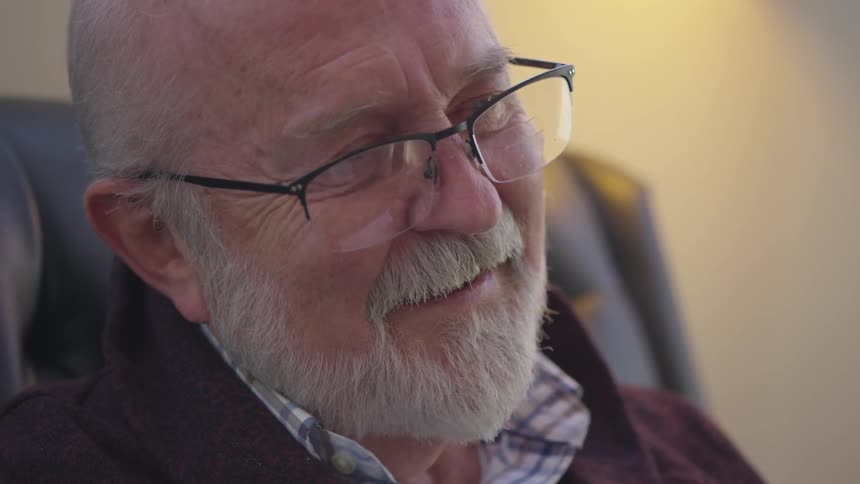 A man sitting in a chair looks up and smiles