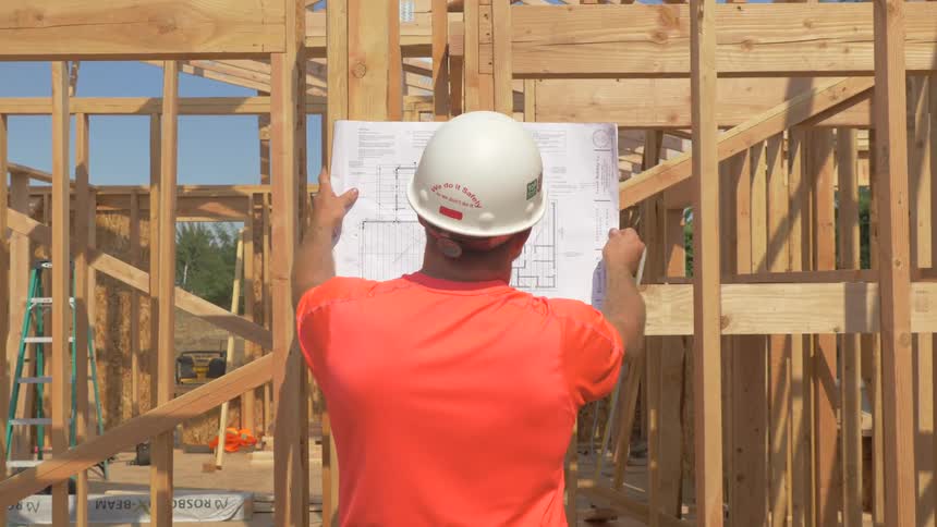 Construction worker is looking at building plans