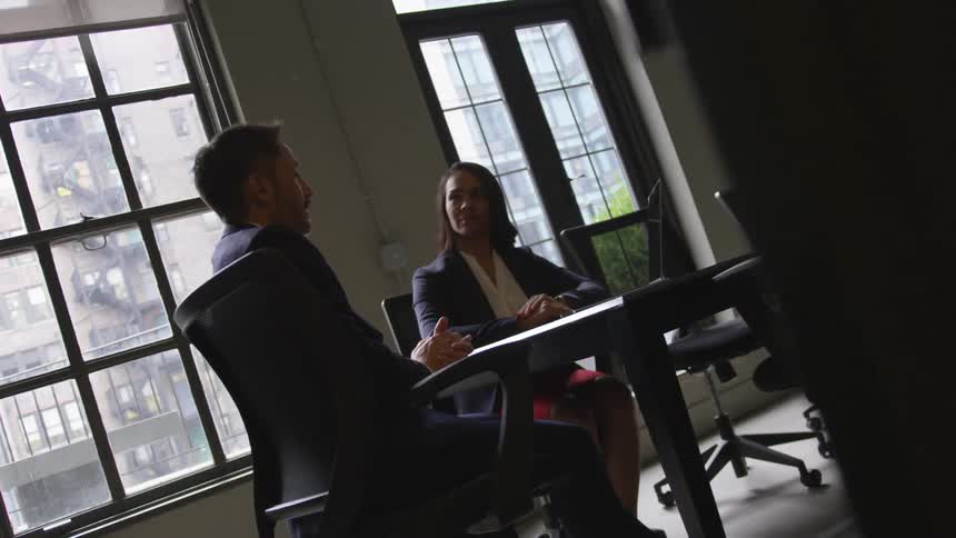 A man and woman sit in the office talking