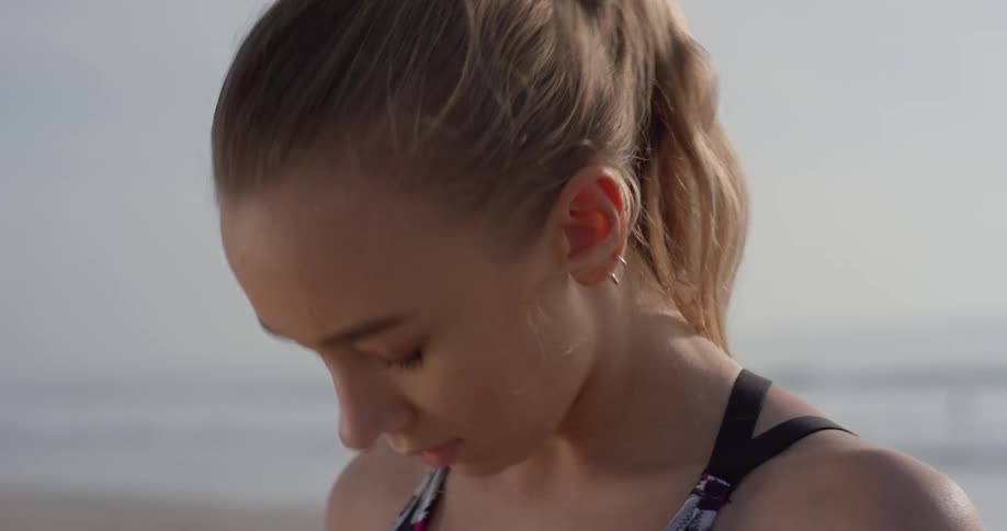 Woman stands outside on the beach stretching