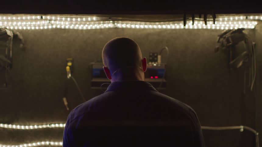 Man sits in a lighted studio sound room
