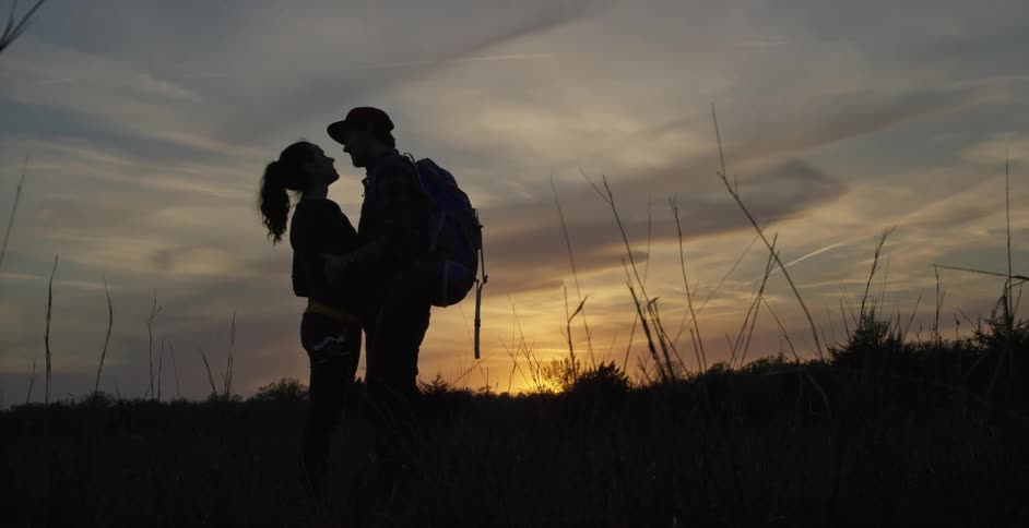 A man and woman embrace during a sunset