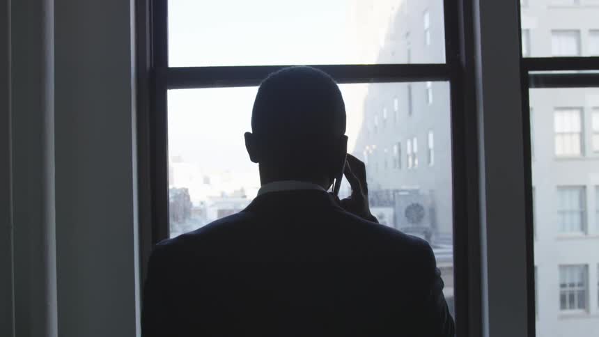 Man talks on the phone while looking out the window
