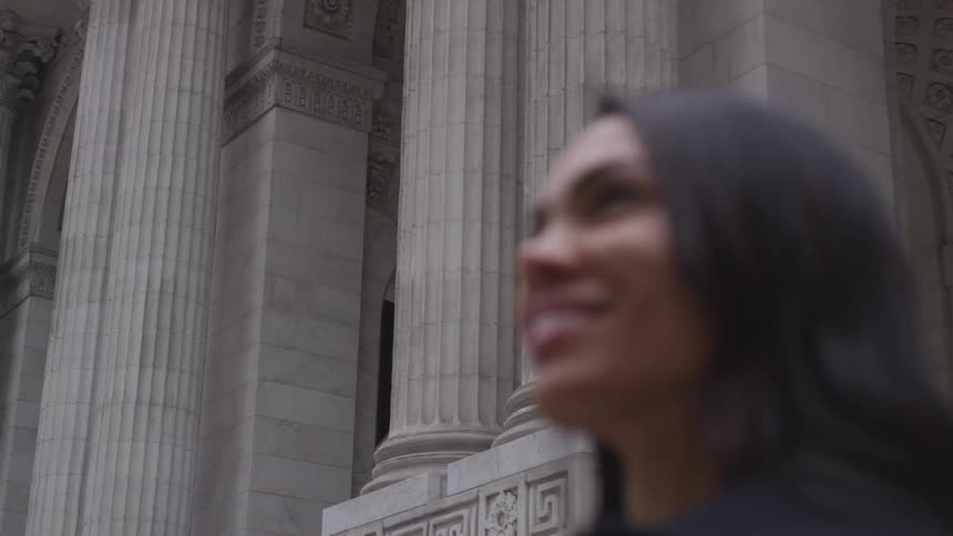 A woman smiles in front of a large stone building