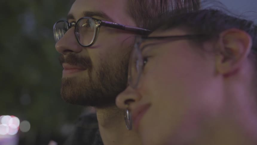 The woman leans on the man in a busy area