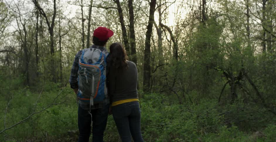 Two people holding hands and walking in forest