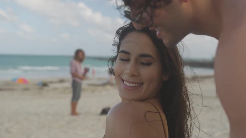A woman is turning to smile at a man who is caressing her shoulders