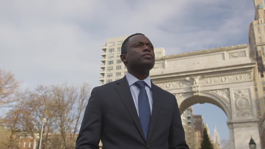 A businessman stands on a city sidewalk