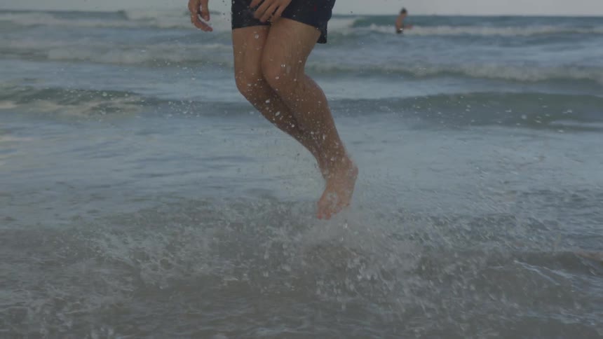 A man splashes and skips in the ocean