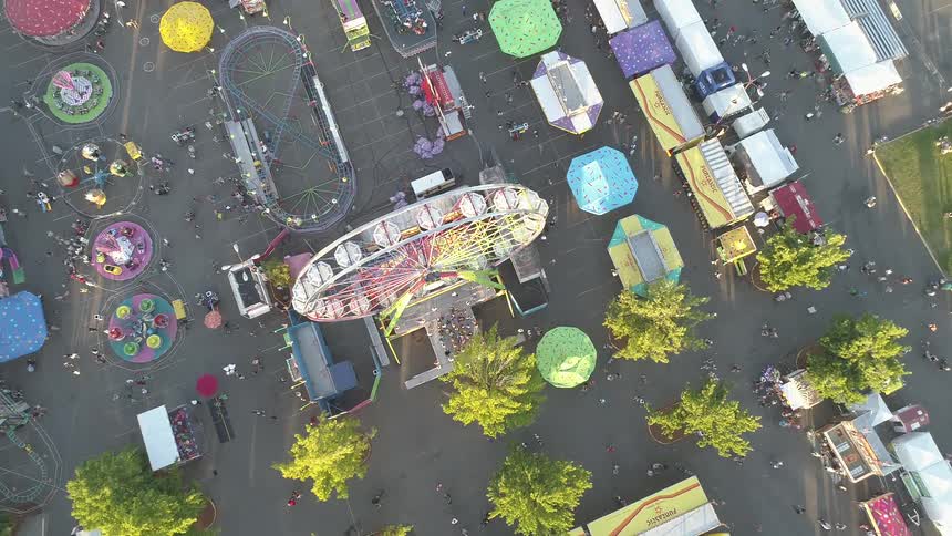 Fairgoers wander around a fairgrounds in daylight
