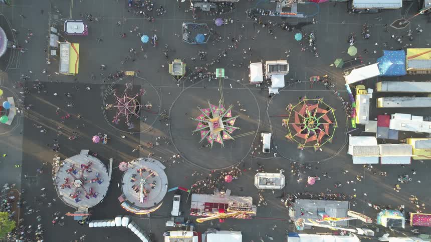 Fairgoers wander around a fairgrounds in daylight