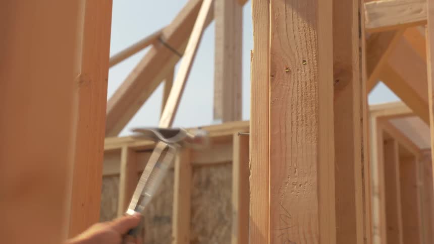 The man hammers a nail into the wood