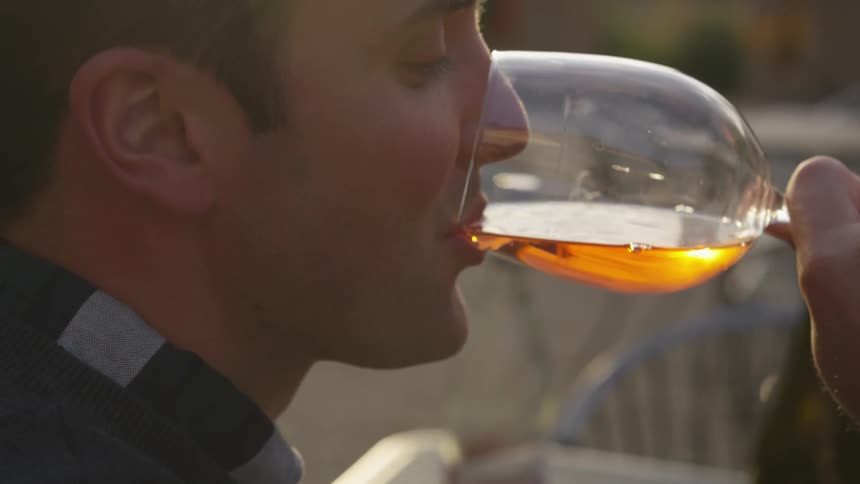Man sips an amber colored liquid from a goblet