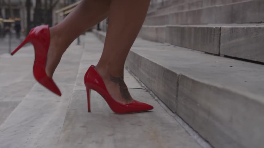 A woman wearing red high heels climbs the steps