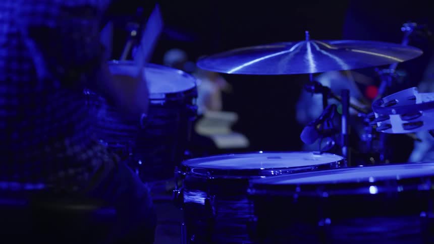 A man plays the drums in the dark