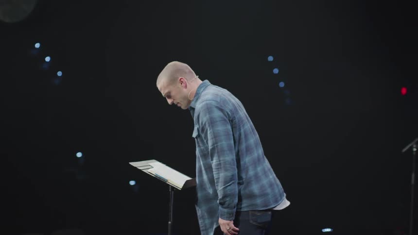 A man speaks in front of a podium on stage