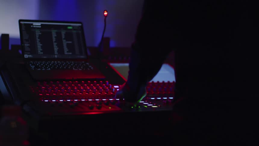 A man adjusts knobs on sound mixing equipment