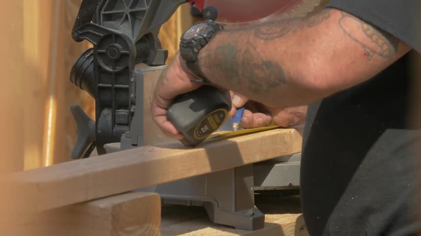 A construction worker is measuring a beam