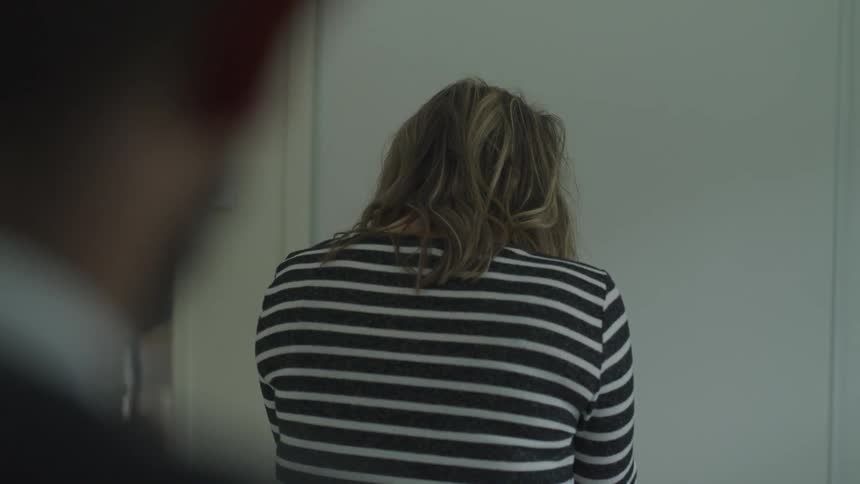 The woman leaning forward against the wall