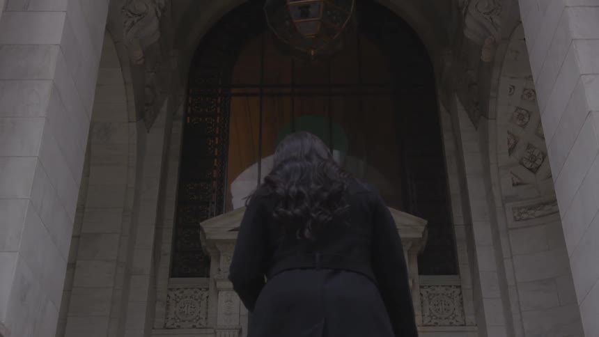 A woman walks up towards the stone building