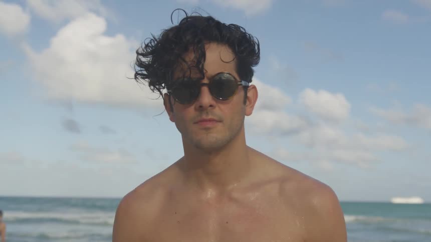 A man stands on the beach by the water