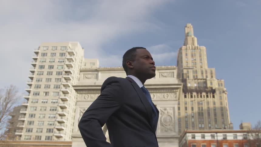 A man walks slowly past the stone building