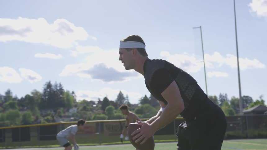 Man holds a football and runs backwards