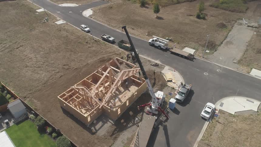A crane is placing a section of a new home