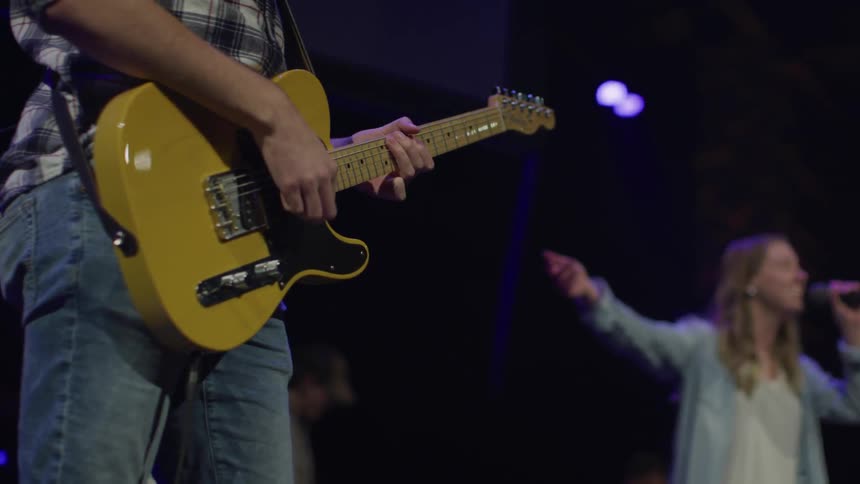 A man strums guitar as a woman sings for a crowd