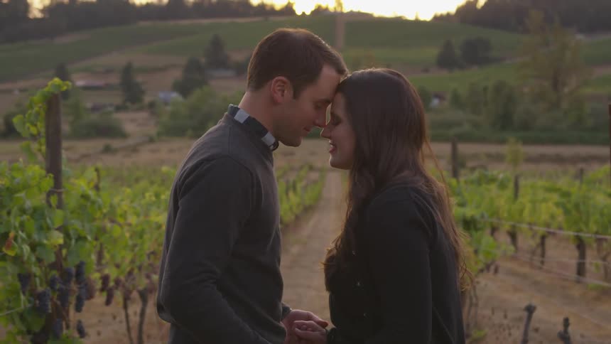 Man and woman hold hands and stand together in a field of crops
