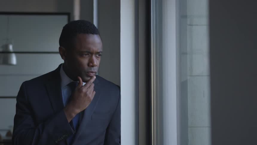 Man stands and thinks while looking out a window