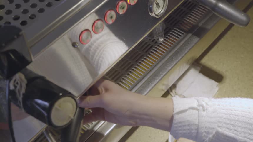 A barista is preparing to make an espresso inside a shop in daylight