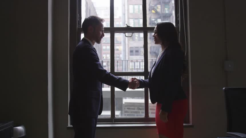 Two business professionals shake hands in an office