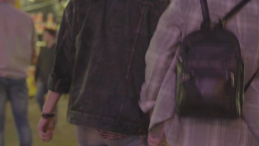 A couple hold hands and walk in the carnival