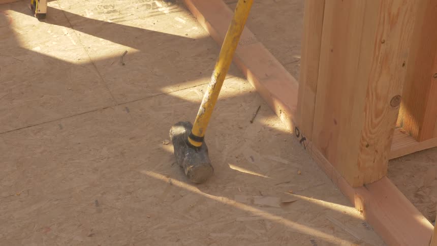 A sledge hammer leans against house framing on a sunny day