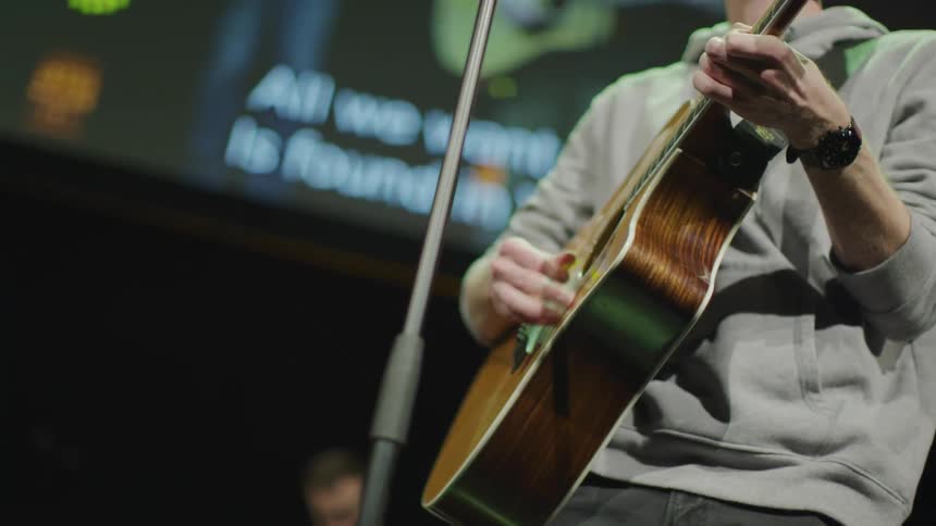 A man strums the guitar on stage