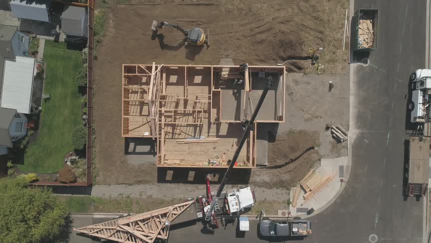 A construction vehicle operates near a house being built