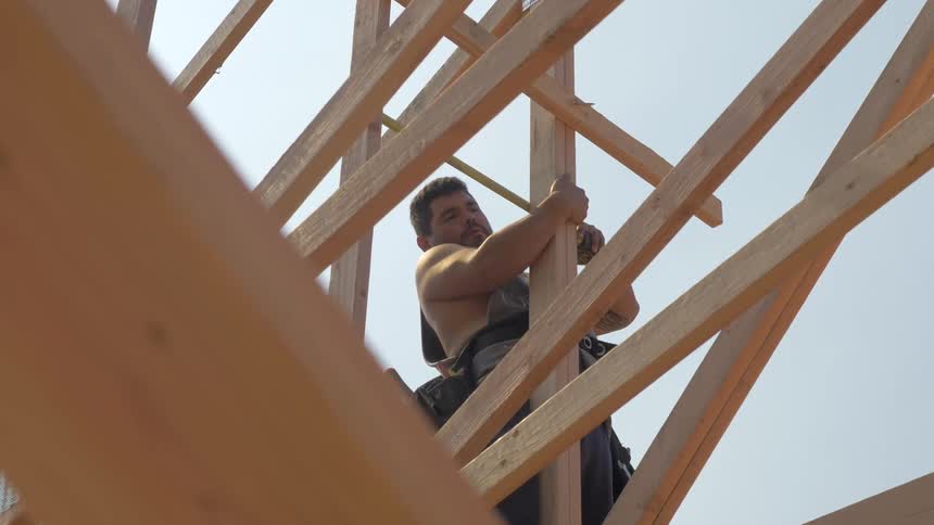 Man measures a wooden beam while holding onto it