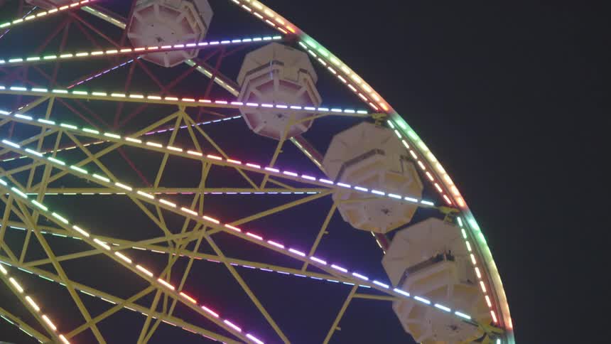 A ferris wheel is rotating at night