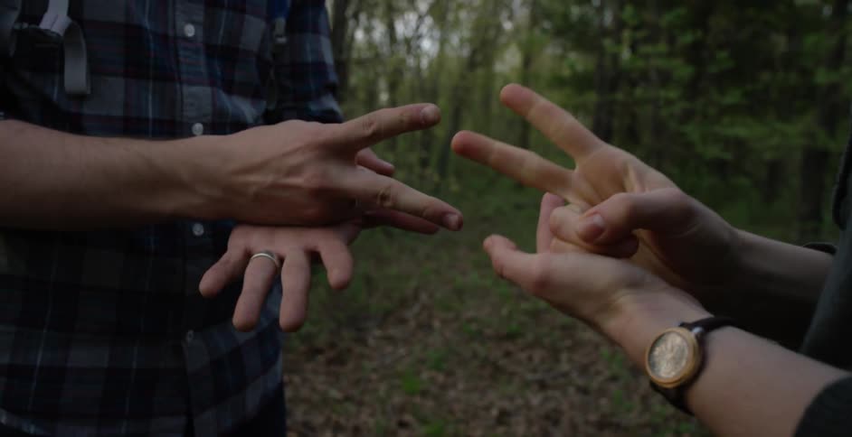 Two people are playing paper, rock, scissors in the woods
