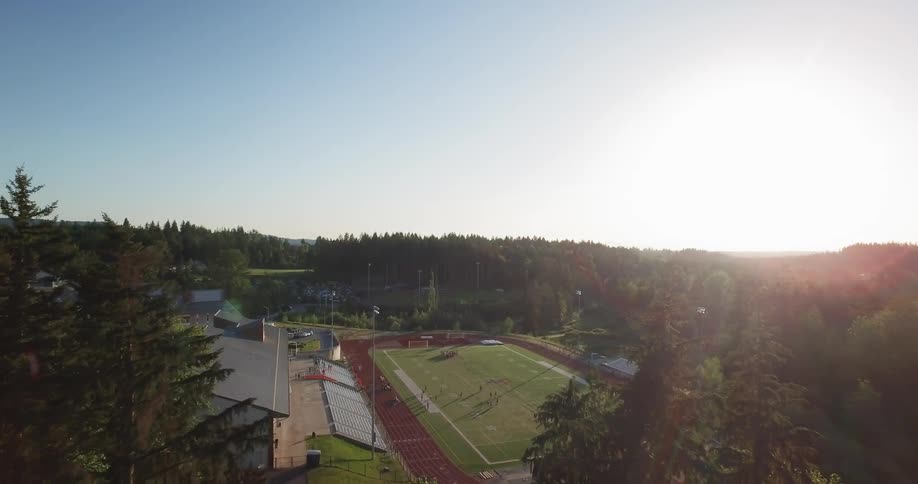 The sun is shining high above the football field