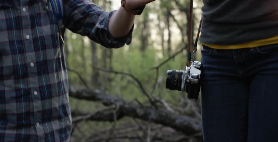 A man helps a woman maintain her balance on a fallen down tree