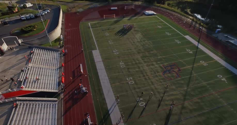 People running and huddling on a football field